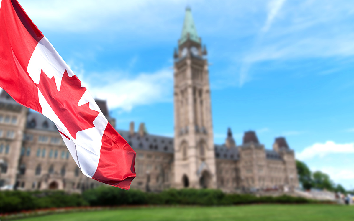 Drapeau canadien avec le bâtiment du Parlement canadien en arrière-plan.