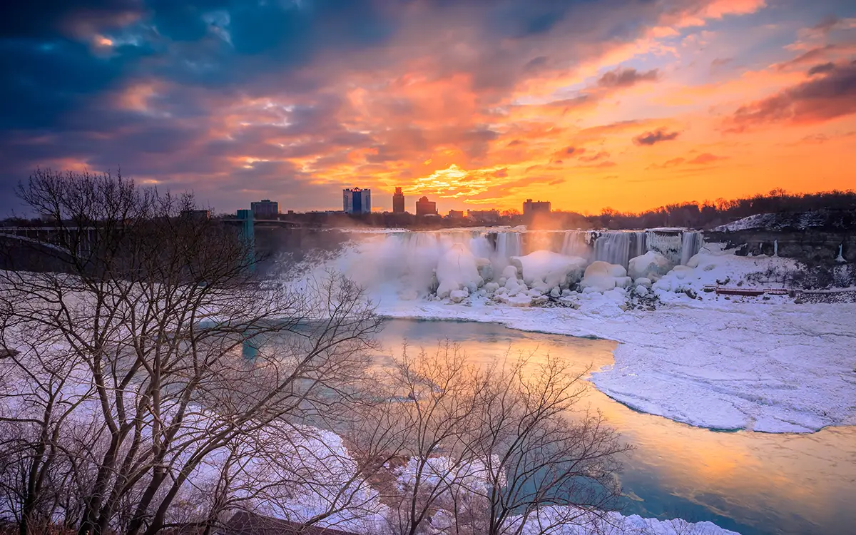sunset over Niagara Falls, as the sun casts a golden glow on the cascading water.