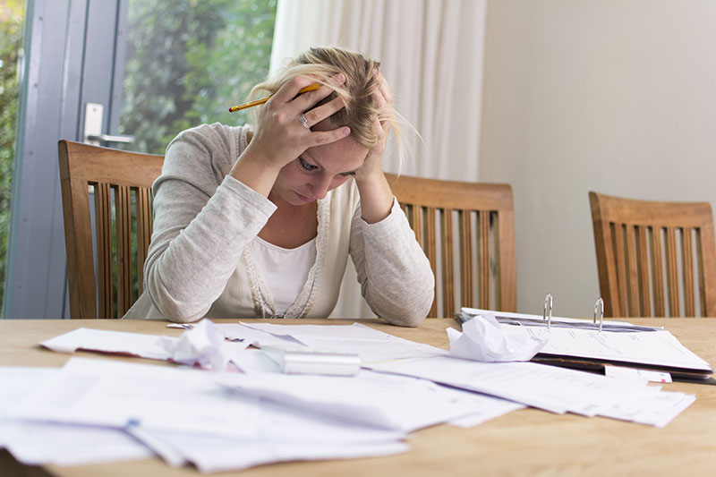 person sitting at a table looking stressed while reading documents