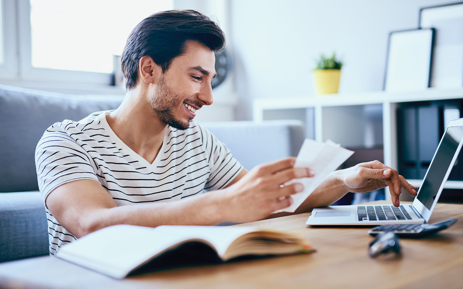 Happy man paying bills on his laptop