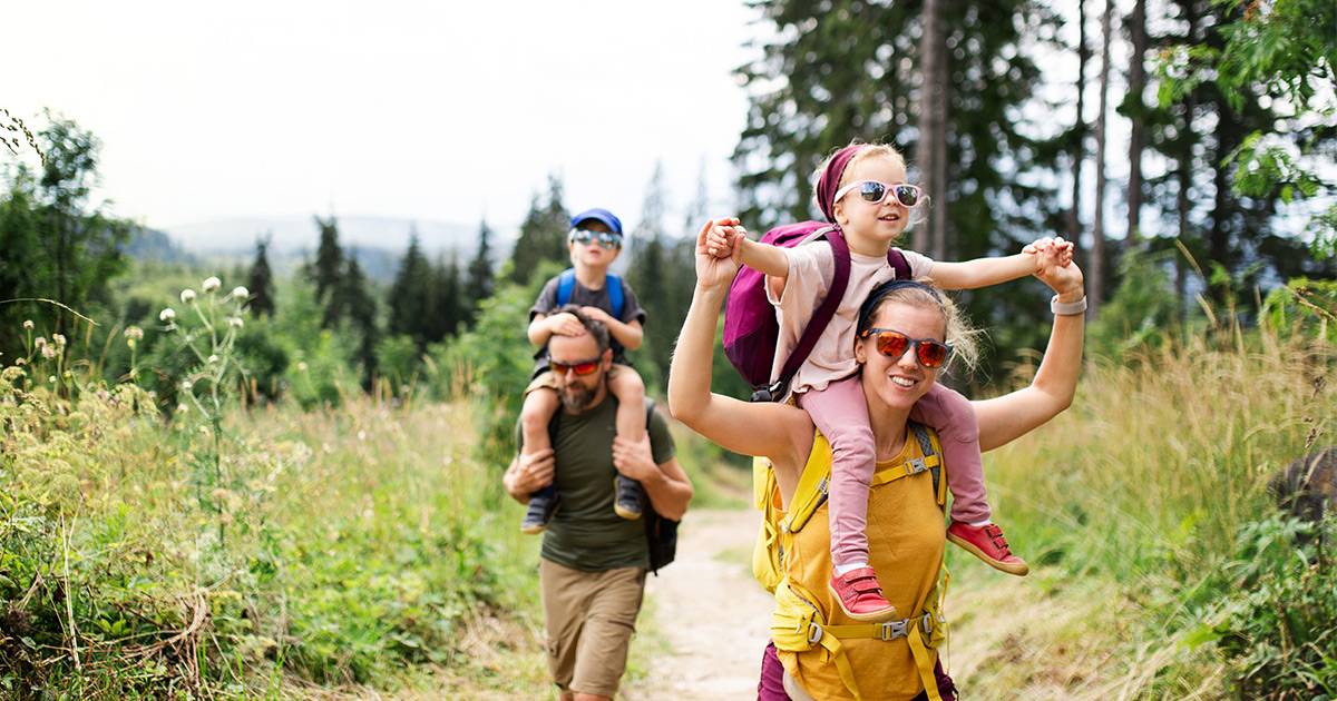 Family with small children hiking outdoors in summer nature