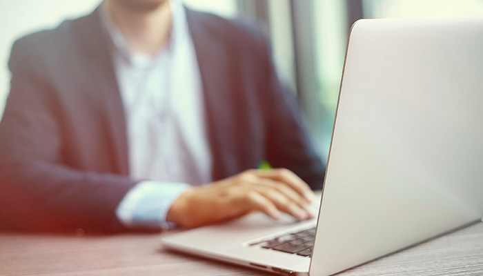 Person in a suit typing on a laptop