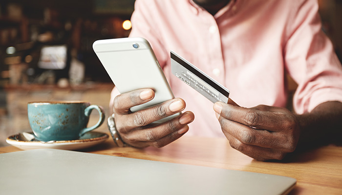 Person at a coffee shop holding their cellphone and a credit card