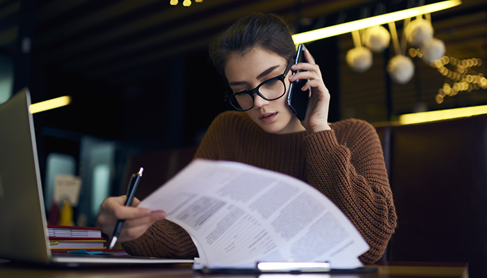 Person talking on their cellphone looking over paperwork