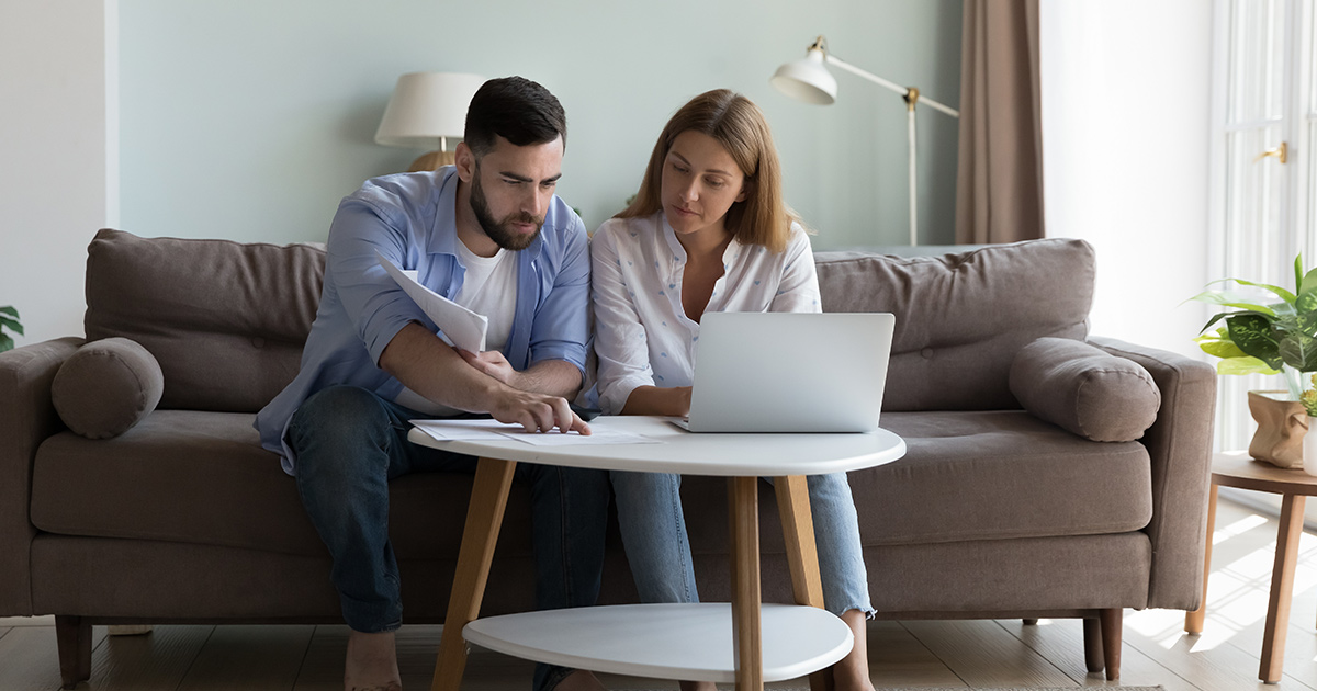 Couple sitting on couch reviewing documents together