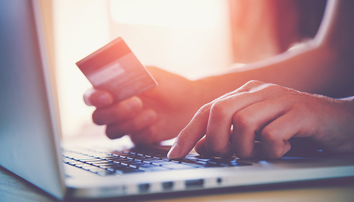 Person on their laptop holding a credit card