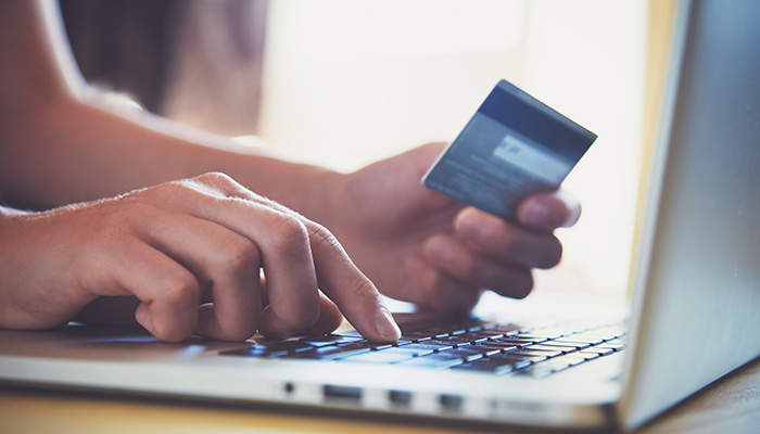 Person online shopping on their laptop holding a credit card