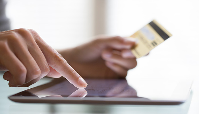 Person on a tablet holding a credit card