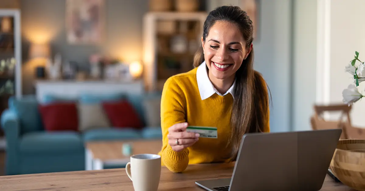 Doing online shopping over laptop with credit card at desk in home office