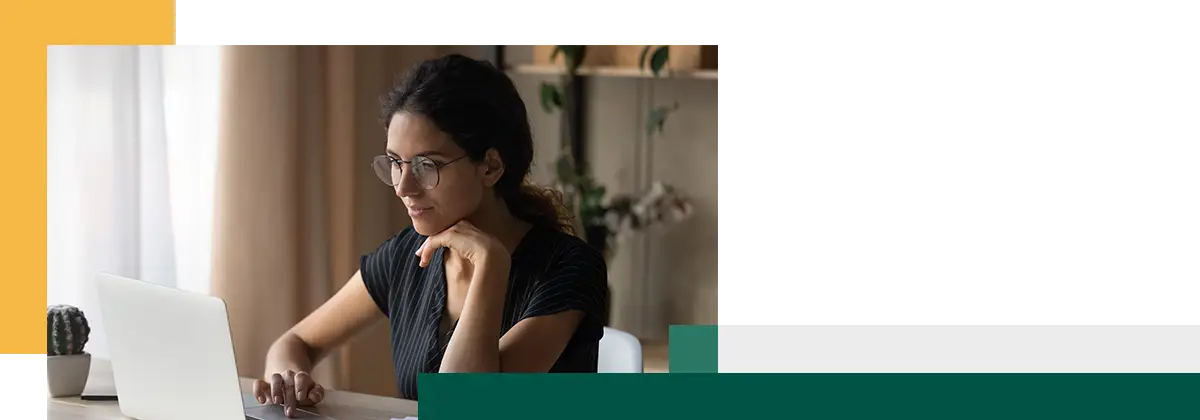 Focused young woman sitting by desk at home working