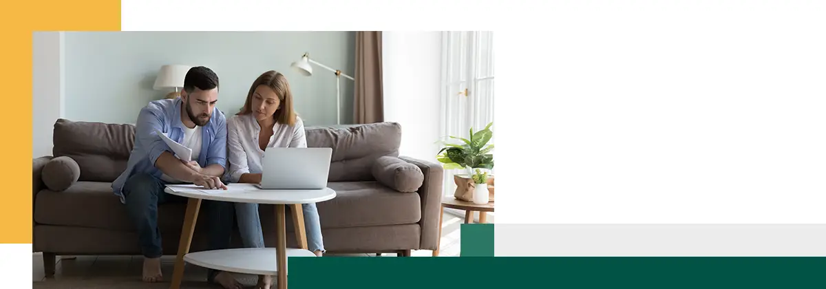 Serious millennial couple sit on sofa sorting out papers