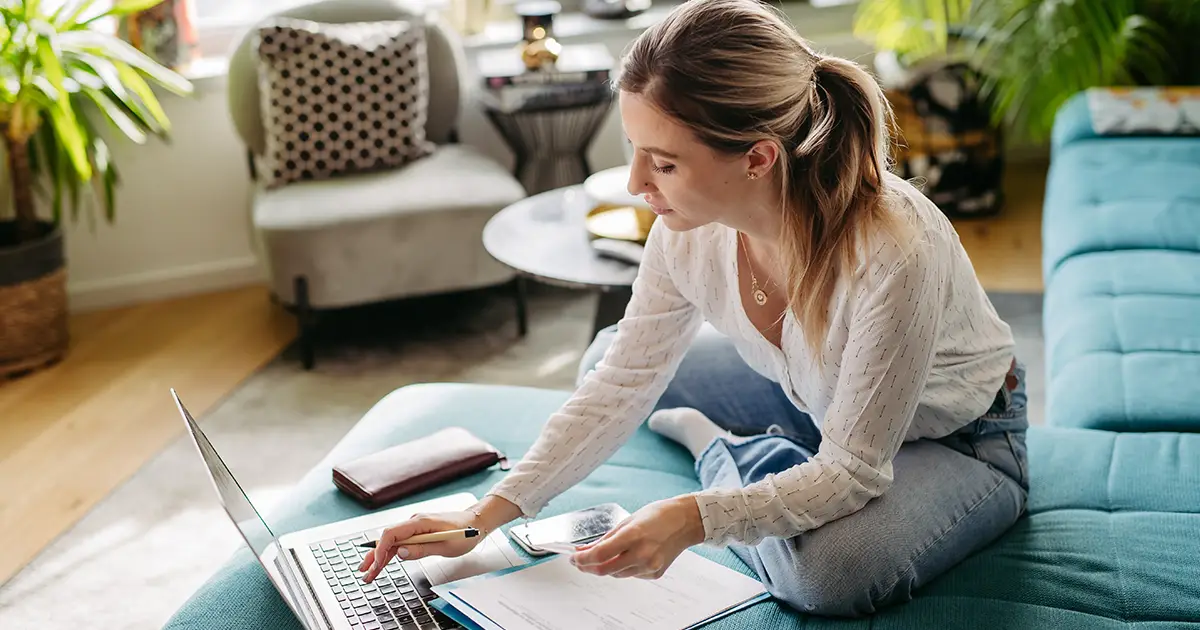 Woman online, sitting in living room, working on notebook