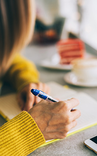 Woman writing pondering on budget writing in notepad