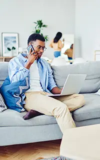 Man on his phone looking at his laptop