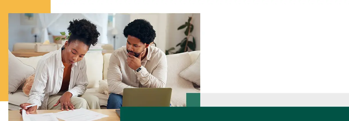Finance documents and laptop with couple on sofa