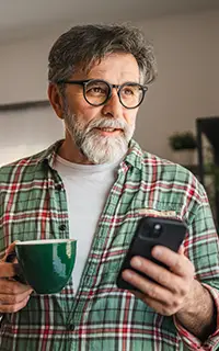 mature bearded man have fun while use mobile phone and drink coffee