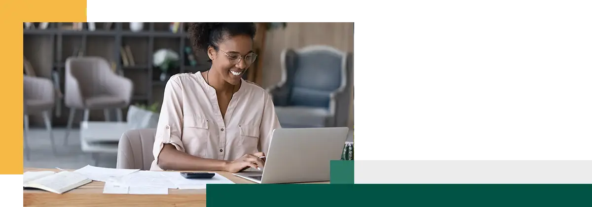 Smiling young female manages student loans online on computer.