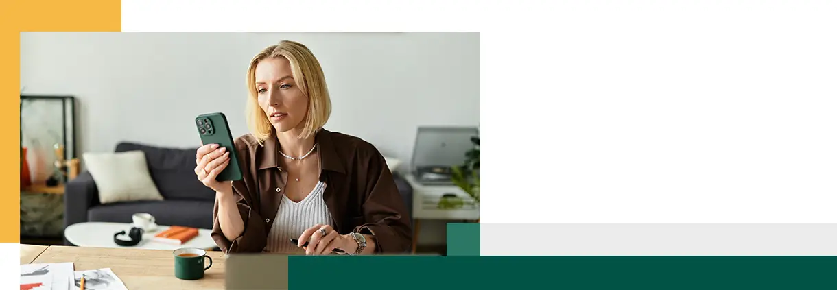 Woman in casual attire sits at home focusing on her phone