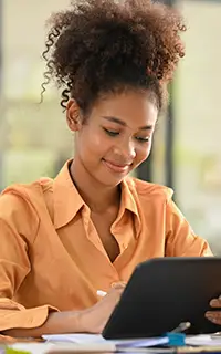 female employee looking at tablet checking online information at her office desk