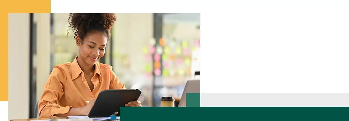 female employee looking at tablet checking online information at her office desk