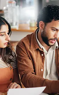 man and woman in kitchen with bills tax expenses or financial discussion