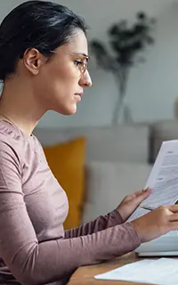 A young woman looking at papers while working with pc