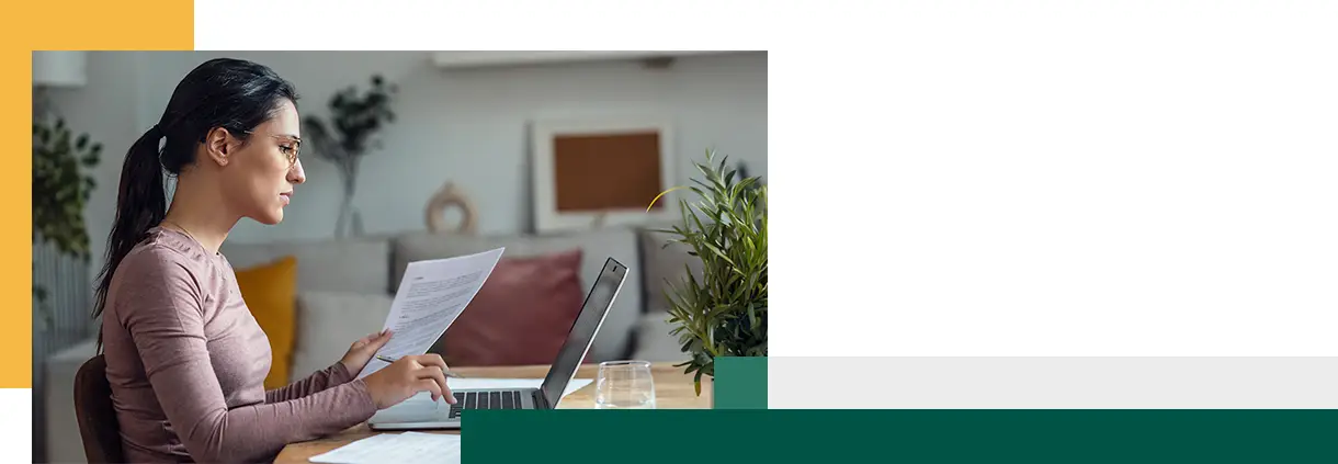 A young woman looking at papers while working with pc