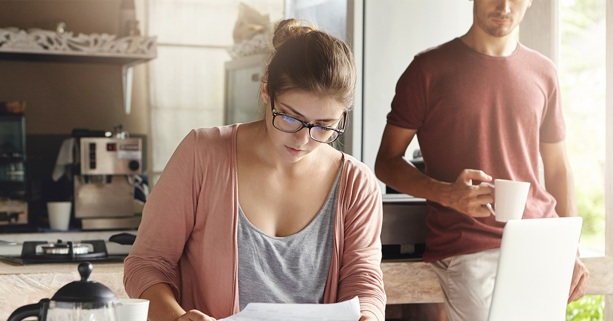 Young woman doing family budget and finances together with her husband at home.