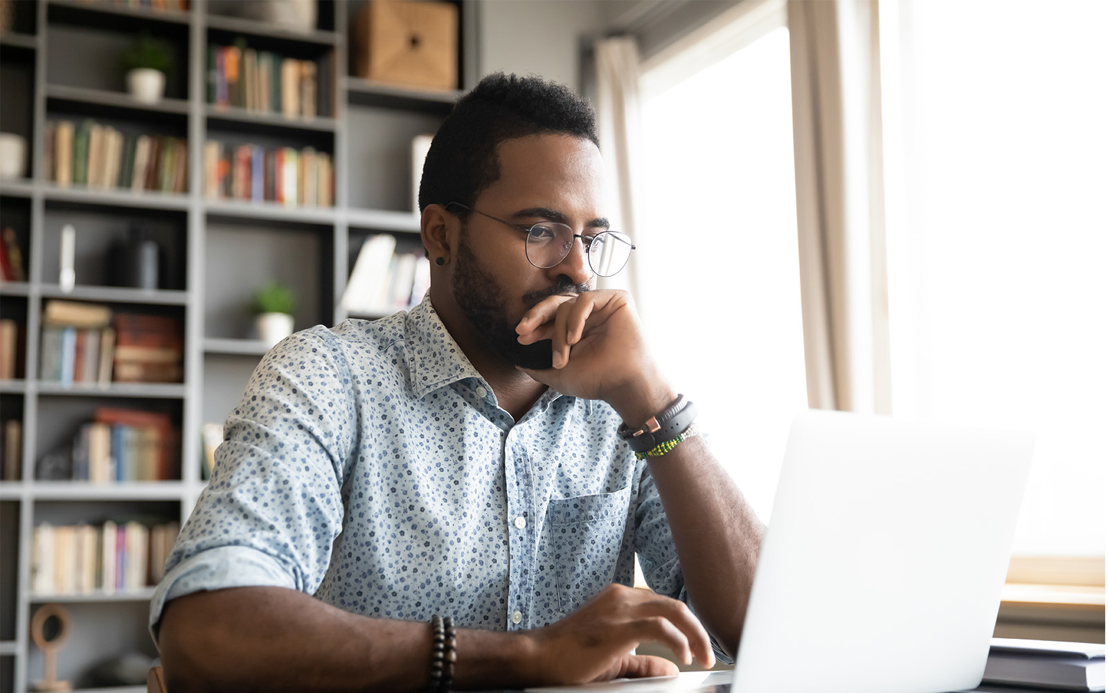 Focused concentrated business person sitting at desk looking at laptop