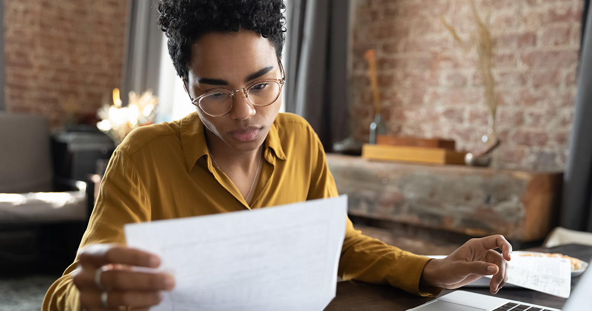 Woman looking through paper documents managing business affairs.