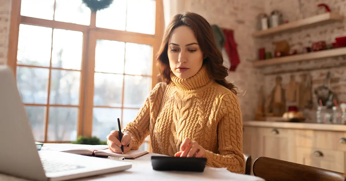 Woman budgeting with calculator during Christmas season.