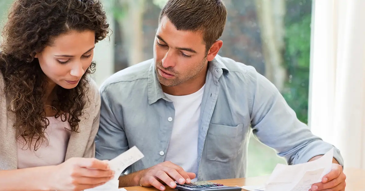 Jeune couple calculant ses factures domestiques à la maison.