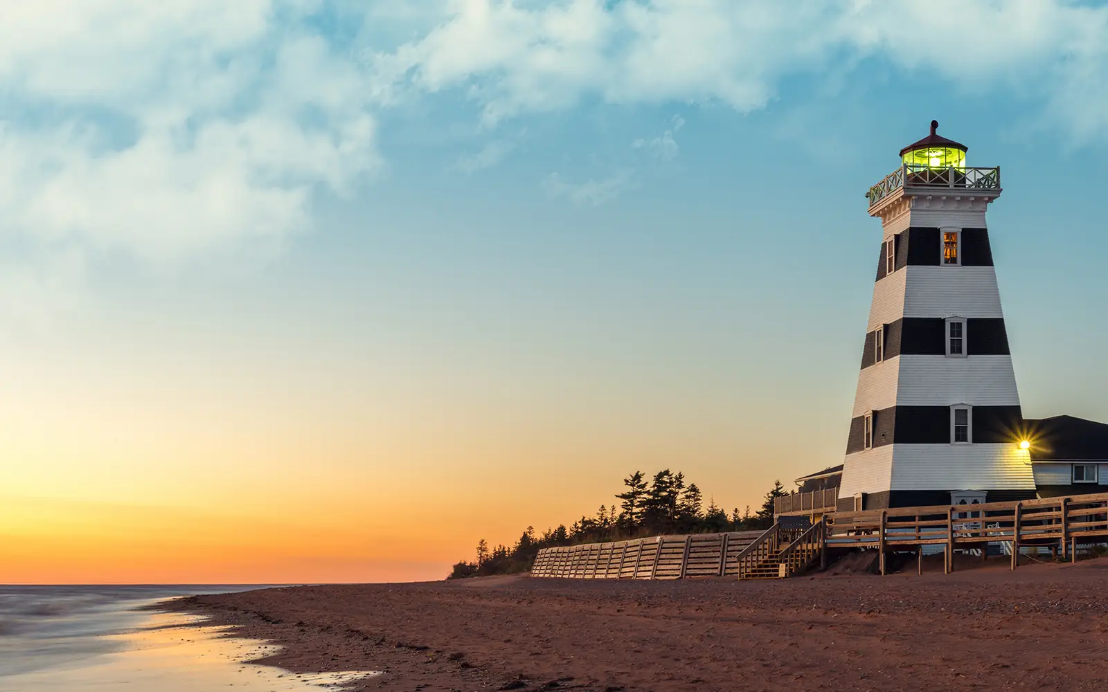Light house during sunset with a beach and water off to the left