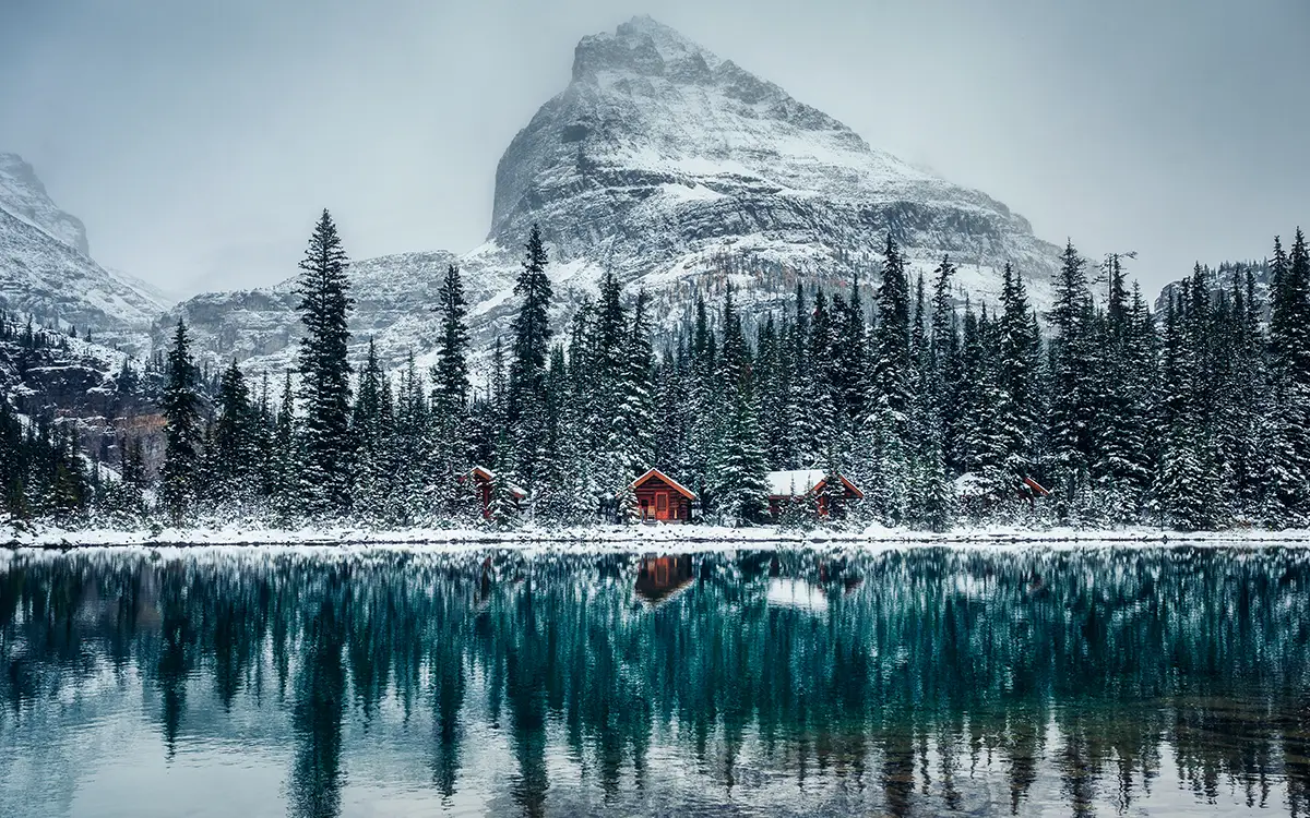 lakeside cabin in front of snowy mountain
