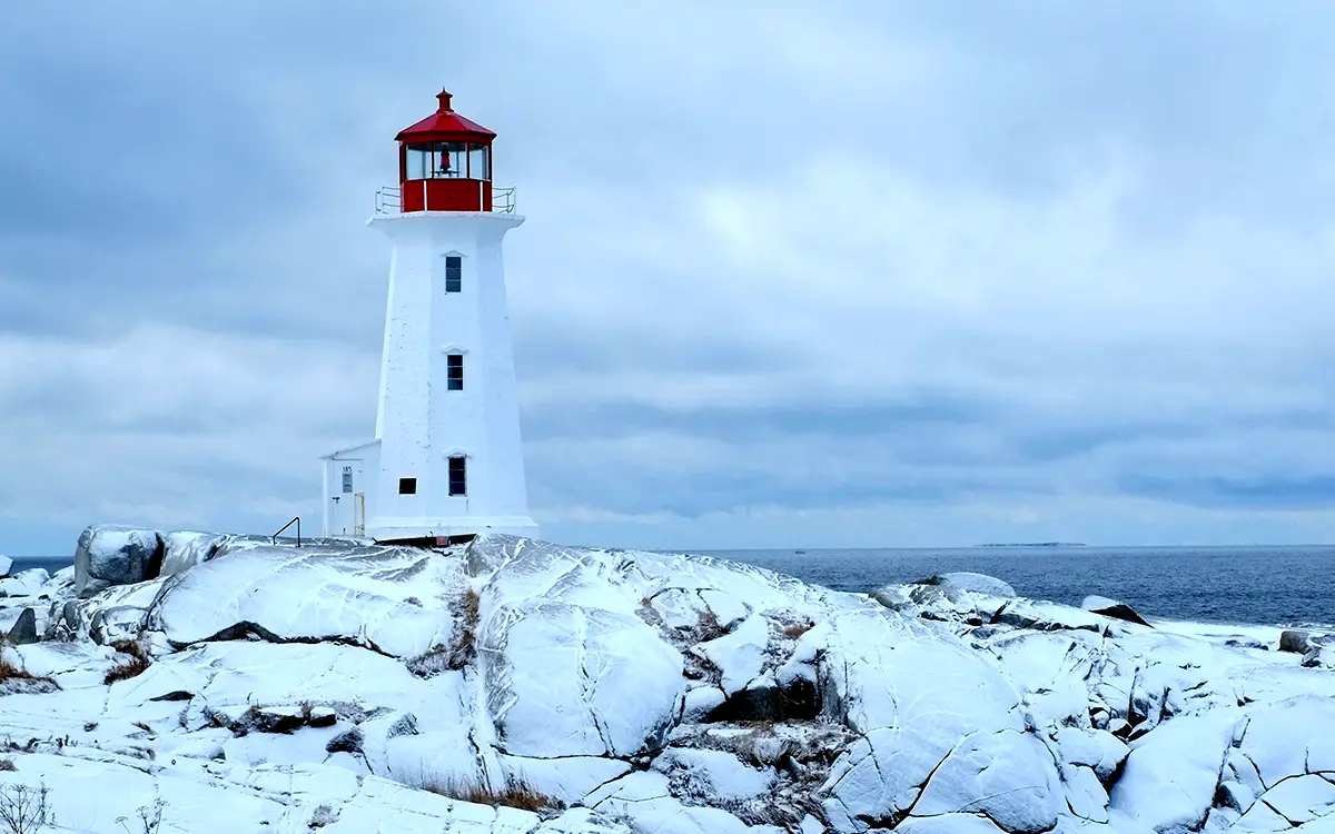 Light house sitting on snow covered rock over looking the ocean