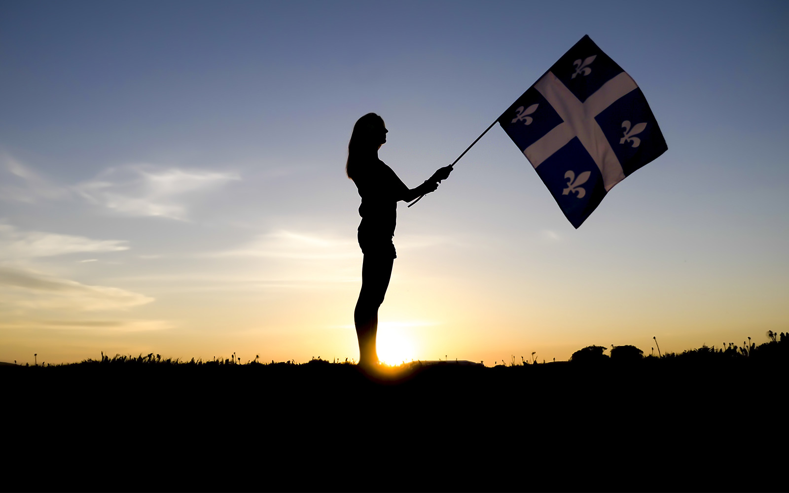 Silhouette of person holding Quebec provincial flag 