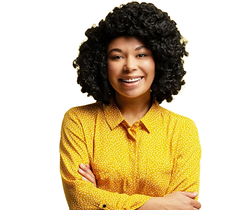 Smiling person with short, curly hair, wearing a yellow polka dot shirt, arms crossed on a plain light background.