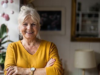 mature woman wearing a yellow sweater smiling.