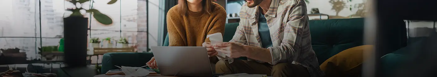 Couple Using Laptop Computer Sitting on Sofa in Apartment
