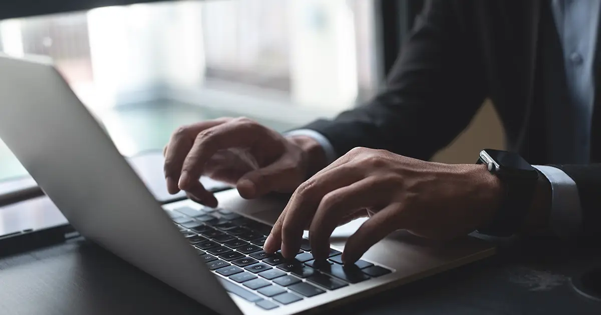 Closeup of businessperson hand typing on laptop computer at office