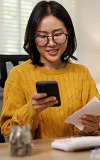 Asian woman calculating expenses and bill payments with a smartphone