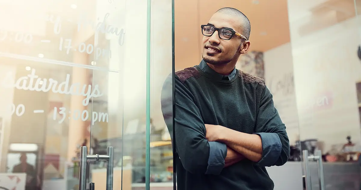 Arms crossed thinking and man at entrance of coffee shop for opening of small business startup