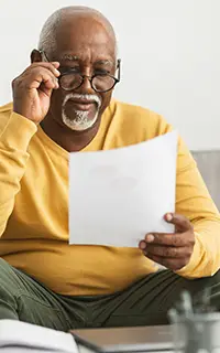 Working With Papers Wearing Eyeglasses Sitting On Couch At Home