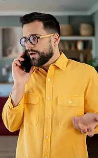 Man in yellow shirt on a tense phone call