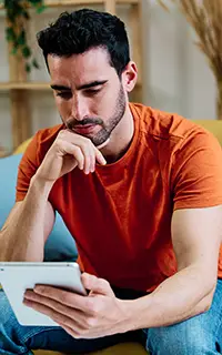 Pensive man using tablet on sofa