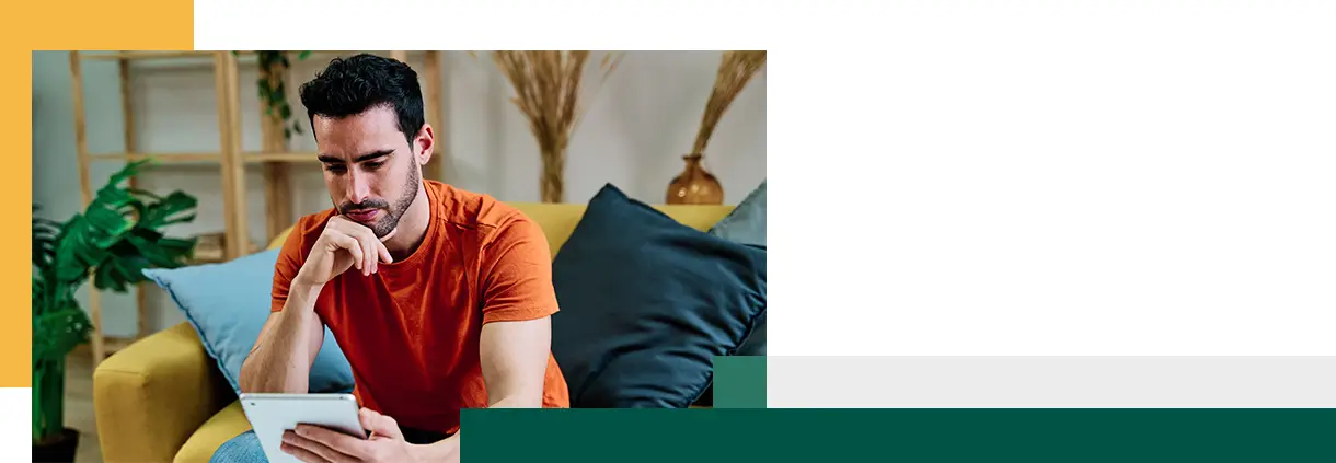 Pensive man using tablet on sofa