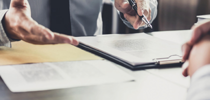 Professional's hands holding a pen over a notepad as they're talking animatedly.