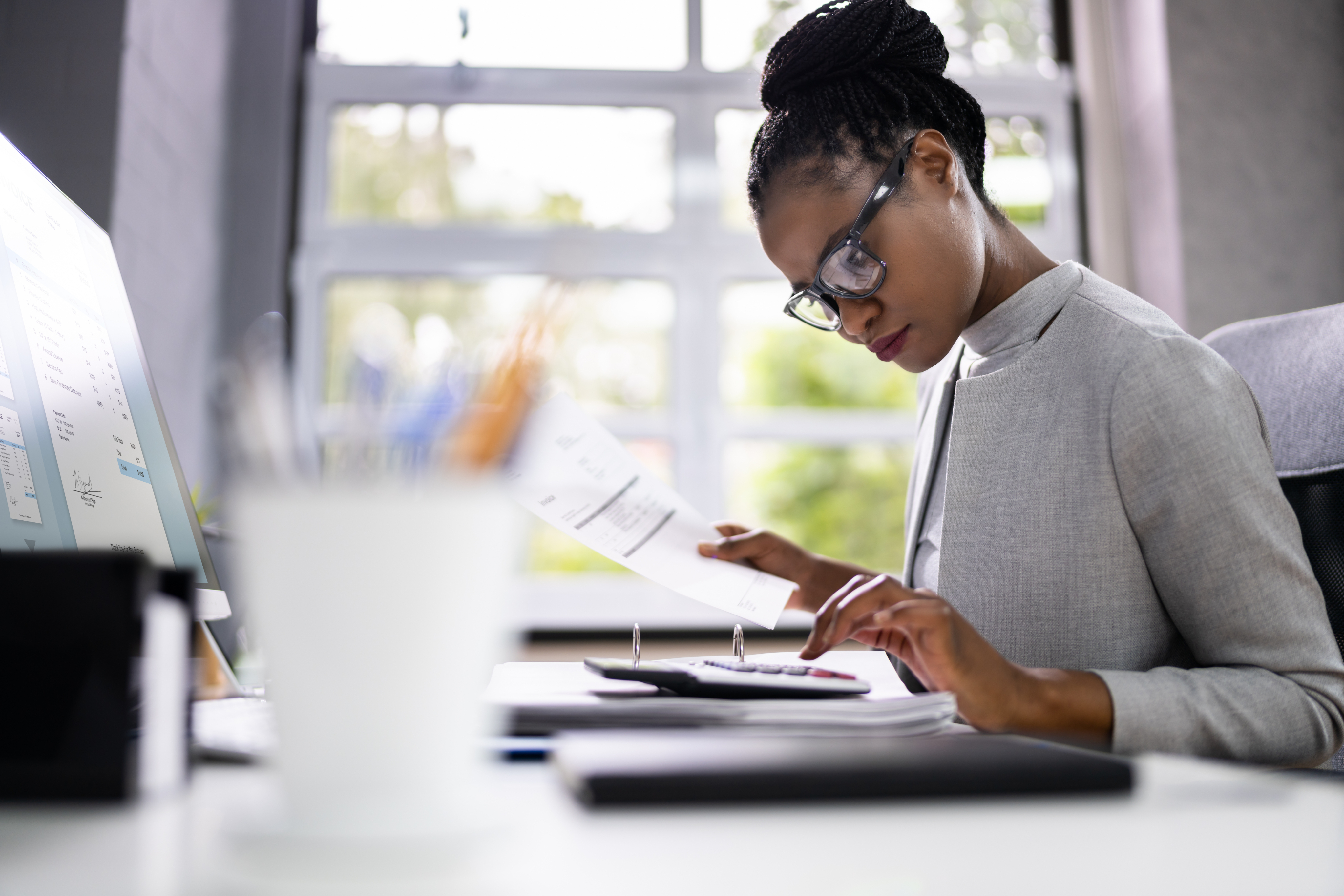 Woman reviewing financial documents and using a calculator to asses her debts.