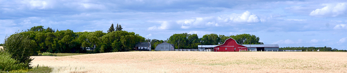 Red barn behind a recently harvested field.