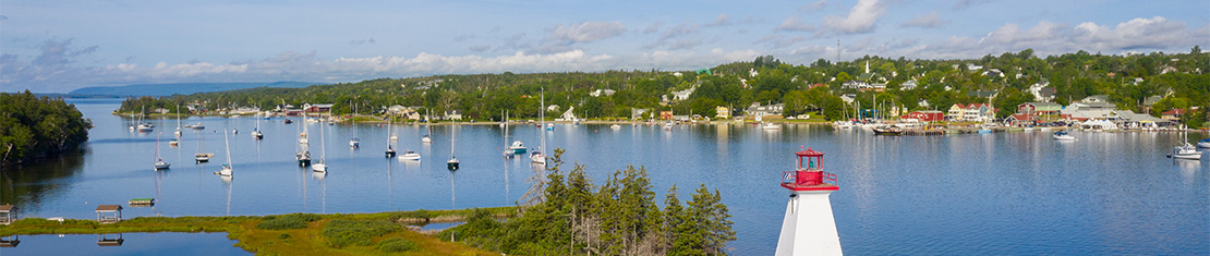Red and white lighthouse overlooking a body of water with a bunch of boats.